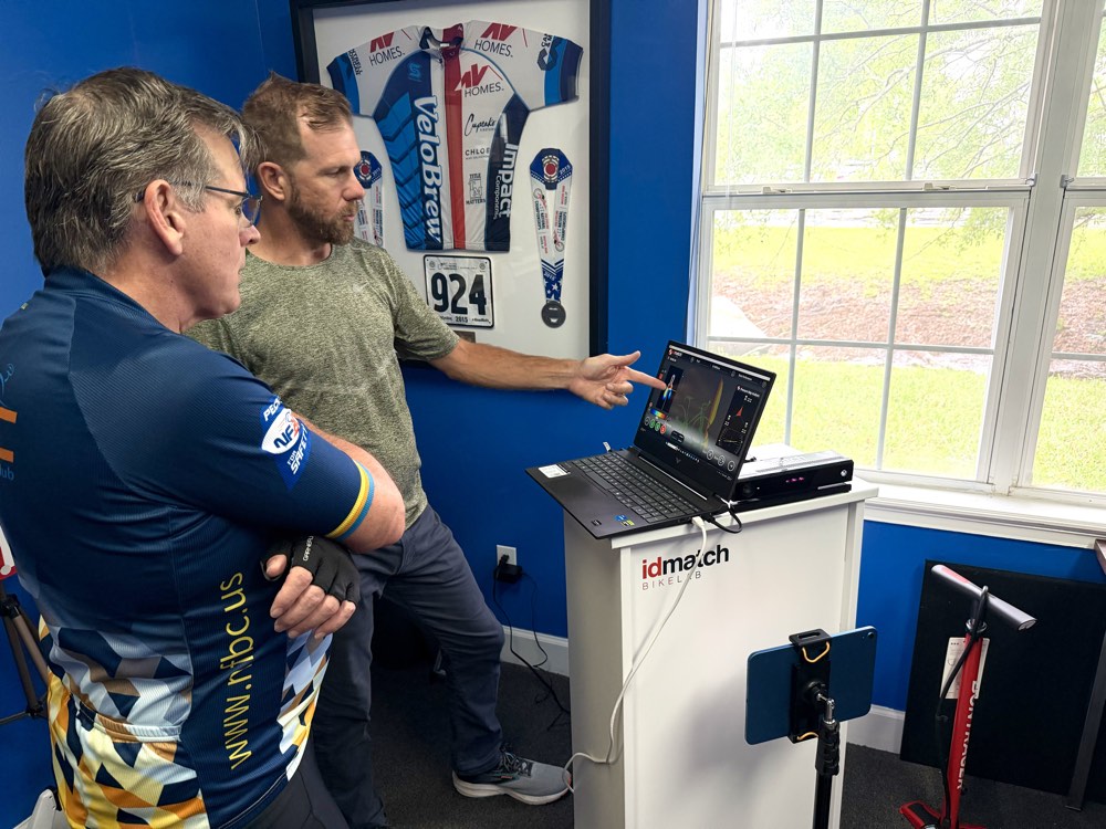 Fitter pointing at IDmatch fit software on a laptop while the athlete reviews the results.