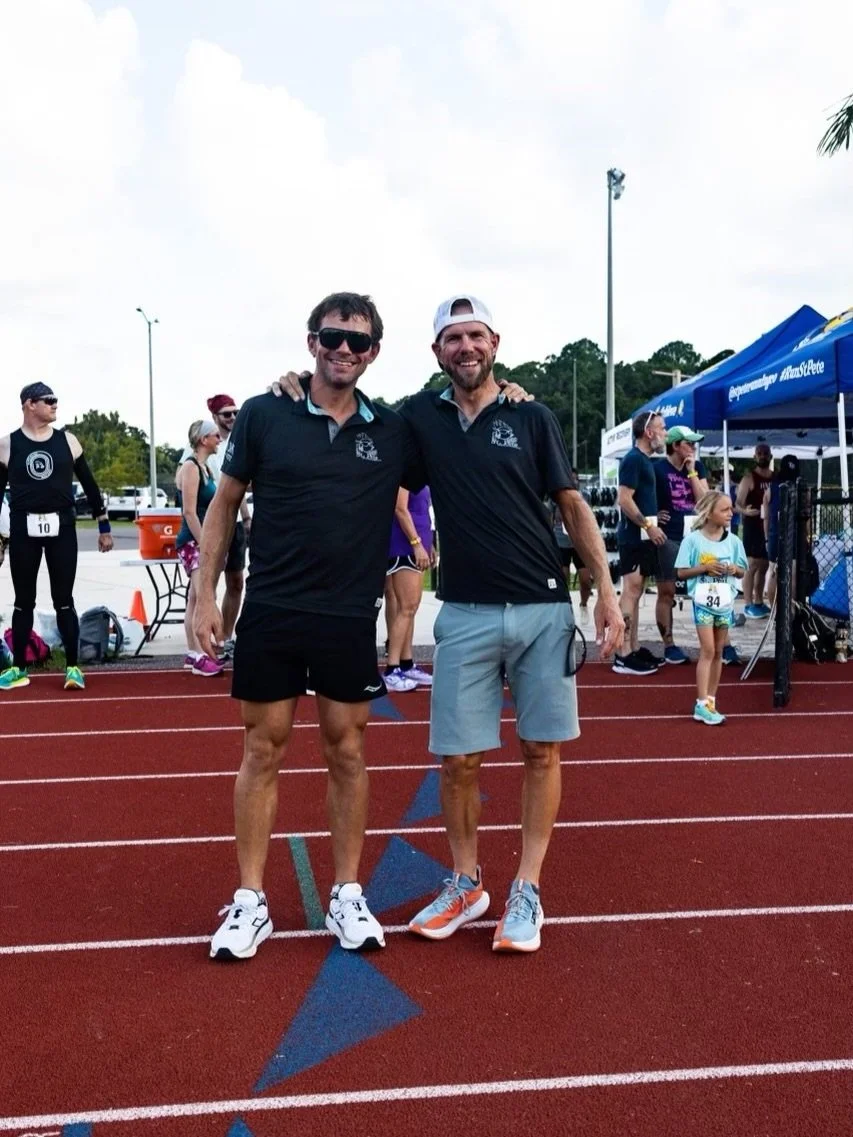 Coaches Owen Shott and Ethan Courson standing together on a running track after a race
